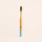 Bamboo toothbrush with blue bristles and handle on a beige background
