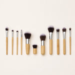 Set of makeup brushes with bamboo wooden handles on a light beige background