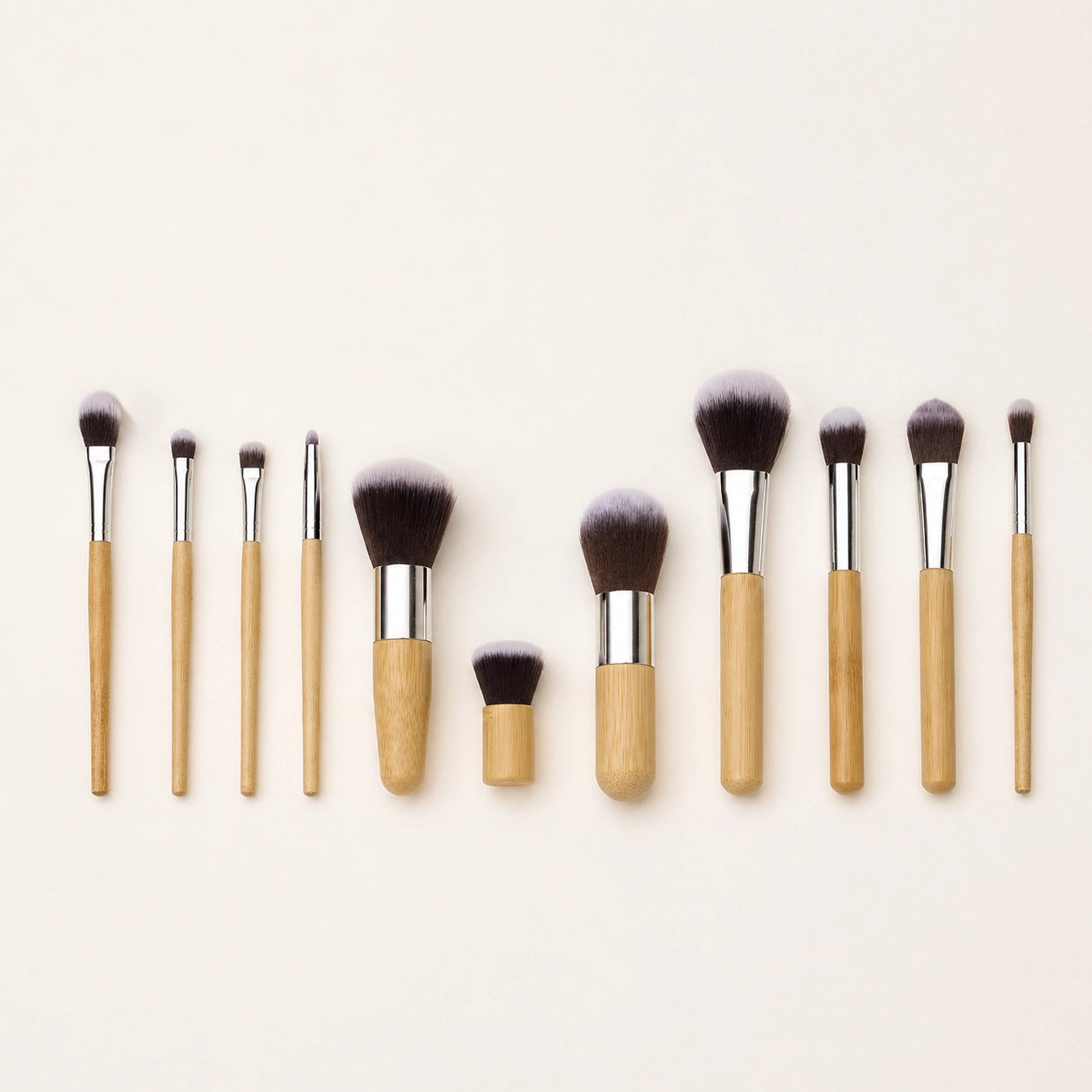 Set of makeup brushes with bamboo wooden handles on a light beige background