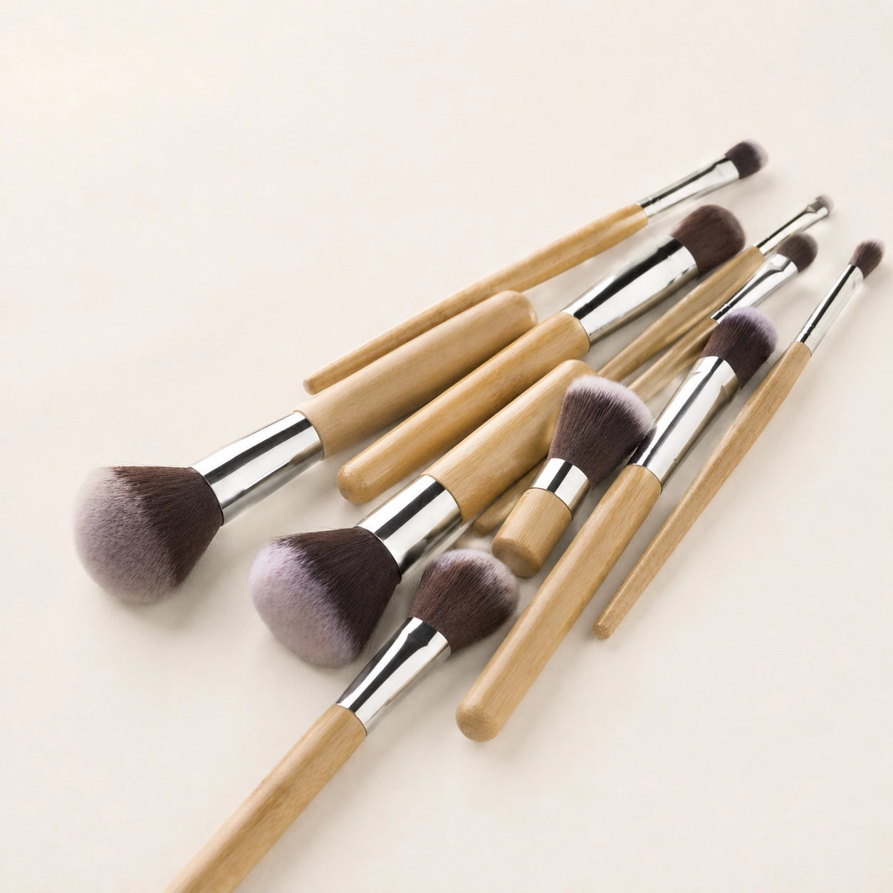 Set of makeup brushes with bamboo wooden handles and brown bristles on a light background