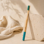 Bamboo toothbrush with blue handle and bristles on a beige background