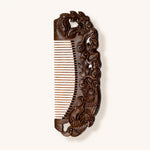 Decorative sandalwood comb with intricate carvings on a white background