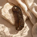 Decorative sandalwood comb on a textured beige surface