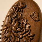 sandalwood hairbrush with floral carvings on a beige background