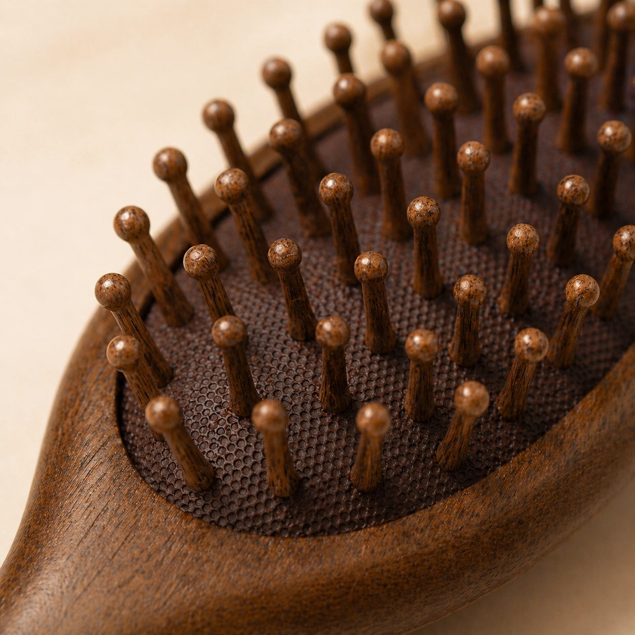 Close-up of a brown hairbrush with sandalwood handle on a beige background
