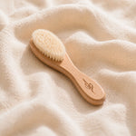 Bamboo newborn baby brush with natural bristles on a soft beige fabric background