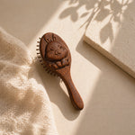 Sandalwood kids hairbrush with decorative handle on a beige fabric background