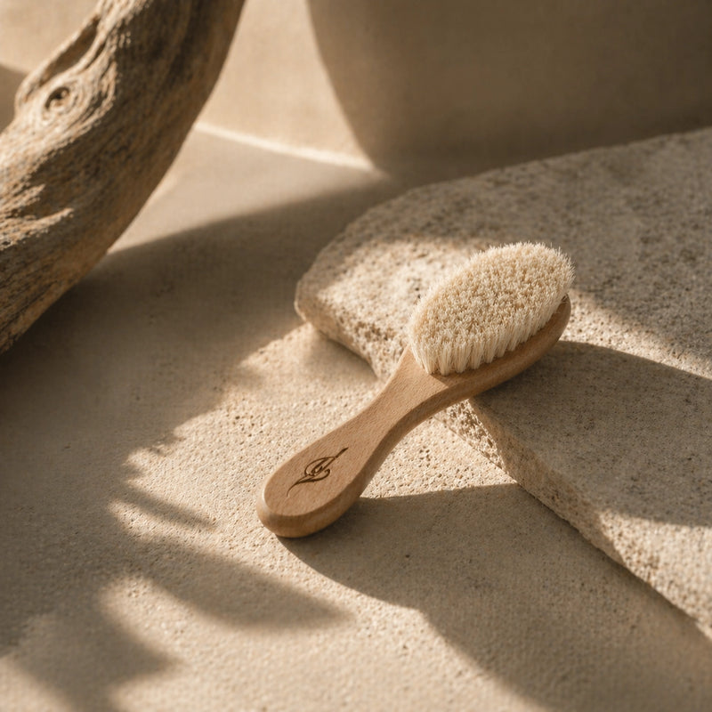 Bamboo newborn brush with natural bristles on a sandy surface