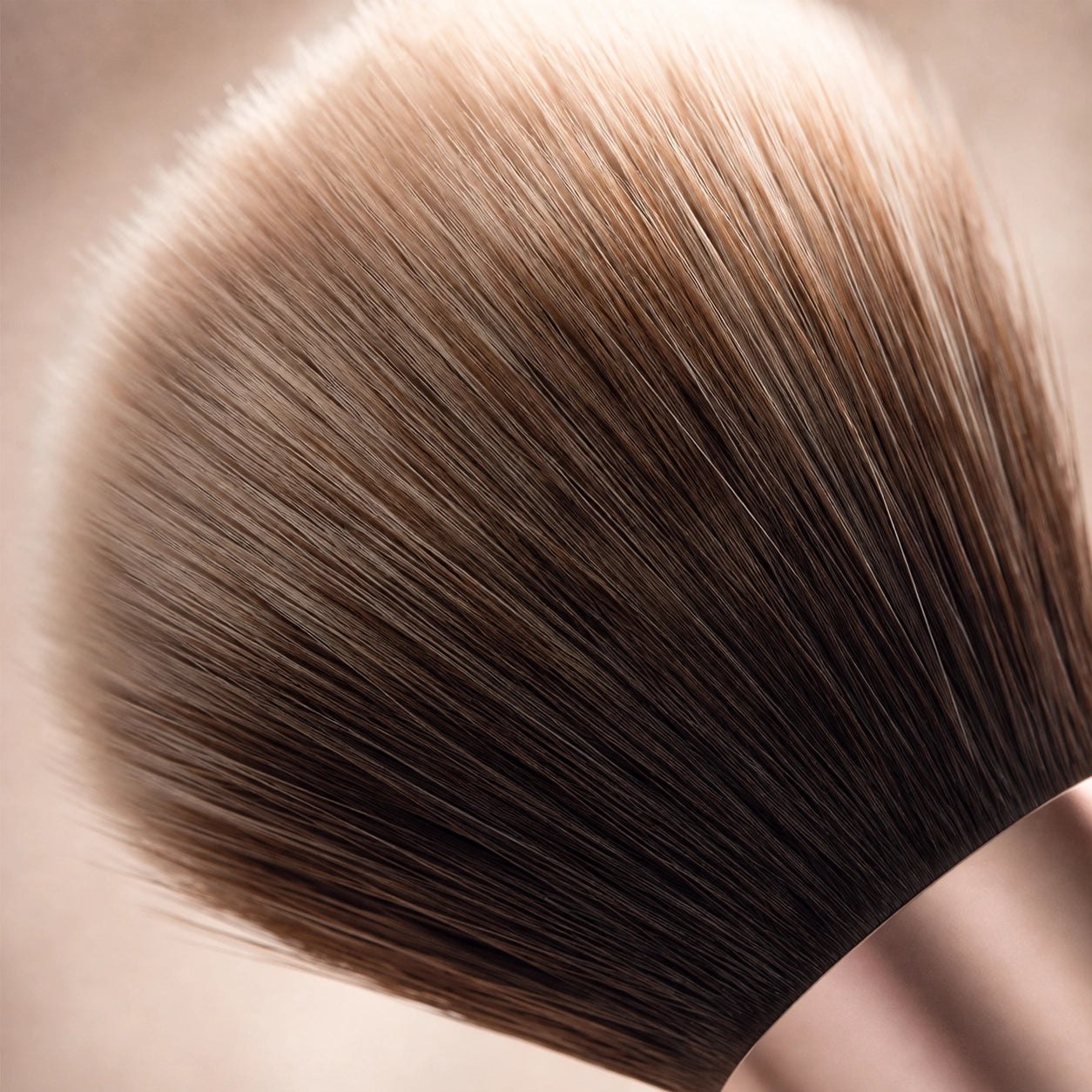 Close-up of a brown makeup hair brush extension on a neutral background